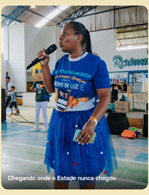 Missionária Paula falando ao microfone em evento da Missão Humanitária